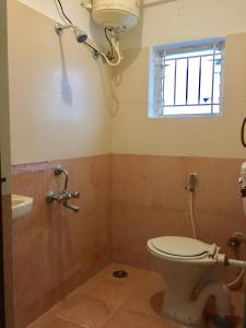 a bathroom with a toilet and a window and a sink at Transit Dorms - A Backpackers Inn & Hostel in Bangalore