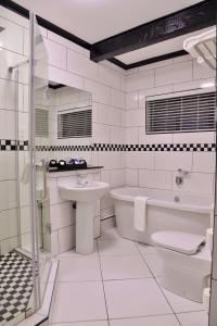 a white bathroom with a tub sink and a toilet at Cresta Churchill Hotel in Bulawayo