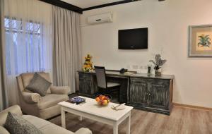 - un salon avec une télévision, un canapé et une table dans l'établissement Cresta Churchill Hotel, à Bulawayo