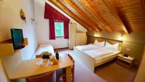 1 dormitorio con cama, mesa y TV en Camping Sass Dlacia, en San Cassiano