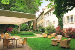 un jardin avec des tables et des chaises et un bâtiment dans l'établissement A La Cour d'Alsace by HappyCulture, à Obernai