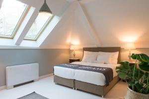a attic bedroom with a bed and two windows at Smokvica Dorćol B&B in Belgrade