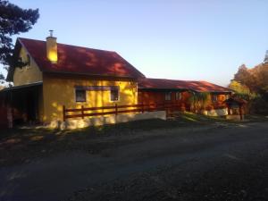 een geel huis met een rood dak bij Penzion U Rozcesti in Lančov