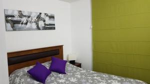 1 dormitorio con 1 cama con almohadas moradas en Departamento En La Serena FULL EQUIPADO, en La Serena