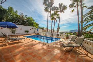 un patio avec des chaises et une piscine bordée de palmiers dans l'établissement San Jaime-19M - sea view villa with private pool in Moraira, à Pedramala