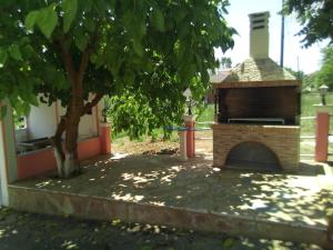 un horno de pizza de ladrillo en un patio con un árbol en Pink House Socrates, en Vitalades