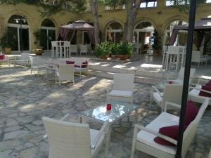 a patio with white chairs and a table with a candle at Messapia Hotel Resort in Leuca