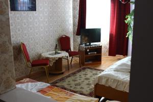 a bedroom with a bed and two chairs and a television at Kálmán Panzió in Szeged