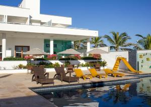 a resort with a pool with chairs and a slide at Pousada Mar Aberto in Beberibe