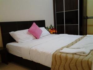 een bed met een roze kussen en witte kussens bij Alisa Homestay in Sungkai