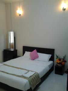 ein Schlafzimmer mit einem Bett mit einem rosa Kissen darauf in der Unterkunft Alisa Homestay in Sungkai