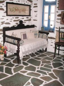 a couch in a room with a stone wall at 3-level doll house in Kea Ioulida/Chora, Cyclades in Ioulis