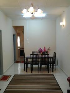 une salle à manger avec une table, des chaises et des fleurs. dans l'établissement Alisa Homestay, à Sungkai