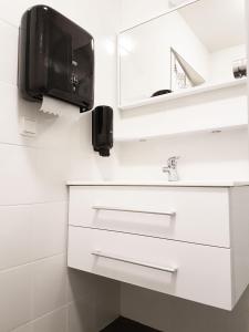 a bathroom with a sink and a tv on the wall at Spirans Rum och Logi in Trollhättan