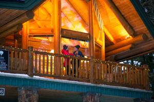 two women standing on the balcony of a log cabin at Snow Creek Cabins by Fernie Lodging Co in Fernie