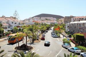 a city with cars parked on a street with palm trees at FN Funchal Tenerife in Los Cristianos