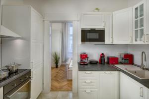 une cuisine blanche avec des armoires blanches et un appareil rouge dans l'établissement Dušní 13 - Old Town Apartment, à Prague