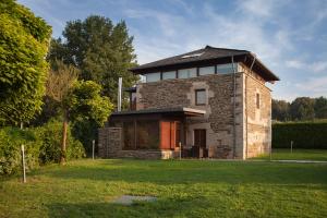 una casa de piedra con techo en un campo de césped en Casa Do Bosque, en Sarria