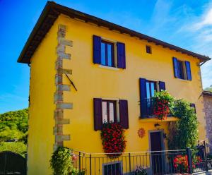 a yellow house with black windows and flowering plants at Villa "Corte de' Baldi" in Ortignano Raggiolo