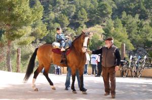a man leading a horse with a child on it at Hotel VegaSierra in Bogarra
