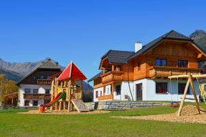 un parque infantil frente a una casa con montañas en Denggnhof, en Weisspriach