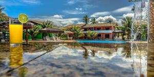 einen Pool mit einem Getränk vor einem Resort in der Unterkunft Hotel Real Comandatuba in Ilha de Comandatuba