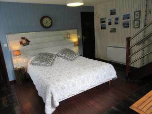 1 dormitorio con 1 cama y reloj en la pared en La Maison de l'Epousée B&B, en Abbeville