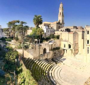 un ancien amphithéâtre devant un bâtiment doté d'une tour d'horloge dans l'établissement Suite del Teatro Romano, à Lecce