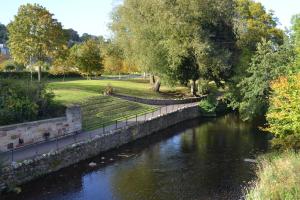 een rivier in een park met een brug erover bij Old Bridge End in Jedburgh