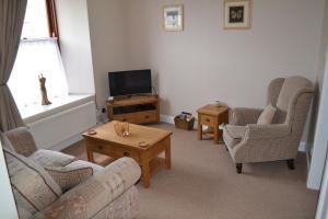 a living room with two chairs and a tv at Old Bridge End in Jedburgh