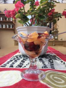 a glass bowl of fruit on a table with a vase at Baytree in Minehead