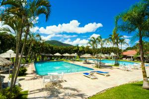 una piscina en un complejo con palmeras y sillas en Aguas Mornas Palace Hotel, en Santo Amaro da Imperatriz