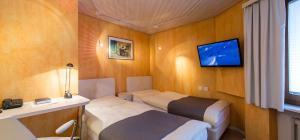 Habitación pequeña con 2 camas y TV. en Seiler's Hotel en Liestal