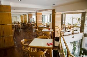 a restaurant with wooden tables and chairs and windows at Hotel Dior in Tandil