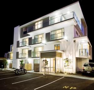 a white building with a motorcycle parked in a parking lot at Focus Motel in Christchurch