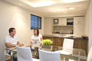 a man and woman sitting at a table in a kitchen at Focus Motel in Christchurch