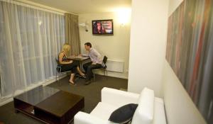 um homem e uma mulher sentados numa mesa num quarto de hotel em Focus Motel em Christchurch