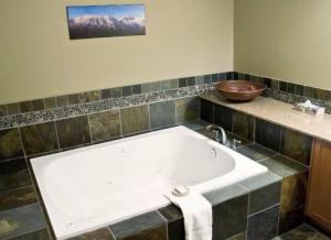 eine große weiße Badewanne im Bad mit Waschbecken in der Unterkunft Pinnacle Ridge Chalets by Fernie Lodging Co in Fernie