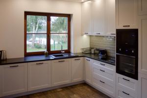 a kitchen with white cabinets and a window at Mazurski Dom nad Jeziorem in Pasym