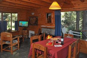 a dining room with a table and a fireplace in a cabin at Paisaje Bandurrias in Villa La Angostura