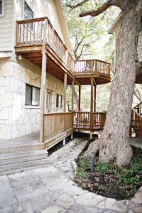 Tiki Lodge 1 في Third Crossing: سطح خشبي على جانب منزل به شجرة
