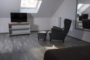 ein Wohnzimmer mit einem Stuhl und einem TV in der Unterkunft Pension am Stummplatz in Neunkirchen
