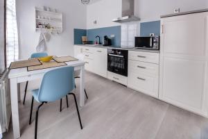 a kitchen with white cabinets and a table and blue chairs at Le République in Châlons-en-Champagne