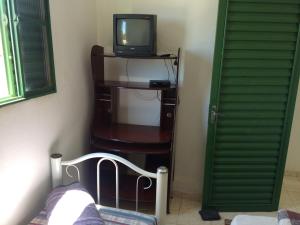 una habitación con TV sentada en una mesa con una silla en Pousada São Jorge, en São Thomé das Letras