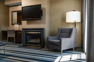 a living room with a fireplace and a chair and a television at Hotel Arts Kensington in Calgary