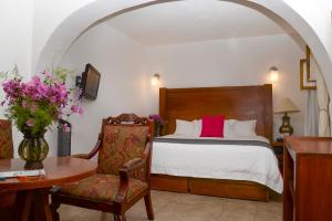 a bedroom with a bed and a table and a chair at El Serafin Hotel Boutique in Querétaro