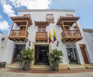 un edificio blanco con balcones y dos banderas. en Hotel Boutique La Artilleria en Cartagena de Indias