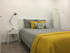 a bedroom with a bed with yellow pillows and a lamp at Lisboa Comfort Apartment in Lisbon