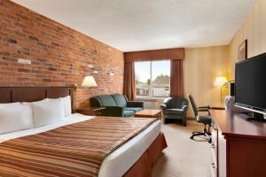 Travelodge by Wyndham North Bay Lakeshore في نورث باي: غرفة فندق بسرير وتلفزيون
