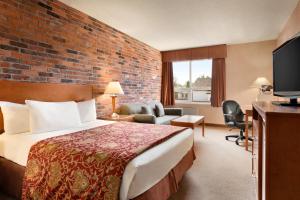 Travelodge by Wyndham North Bay Lakeshore في نورث باي: غرفة فندق بسرير وجدار من الطوب